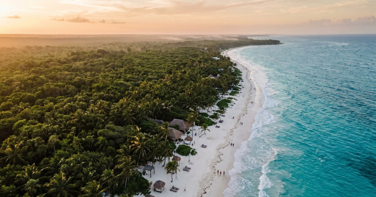 Vista aérea de la Riviera Maya: jungla, playa de arena blanca y mar Caribe turquesa al atardecer